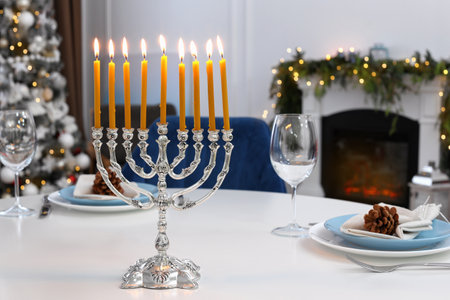 Silver menorah on white table in room with fireplace and Christmas decorations. Hanukkah symbolsの写真素材