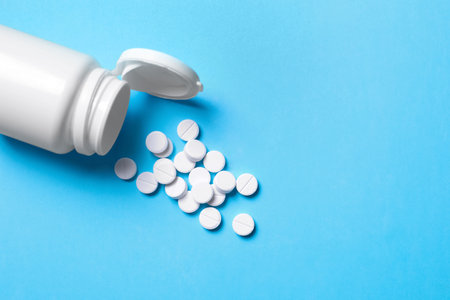 Pills and bottle on light blue background, above view. Space for textの写真素材