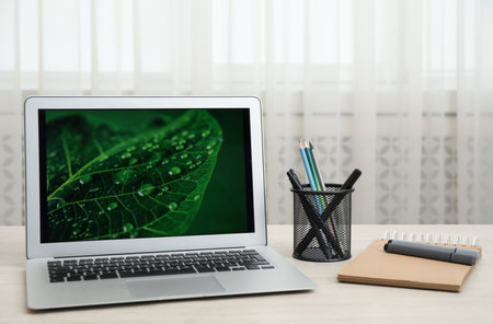 Modern laptop and supplies on wooden table indoors