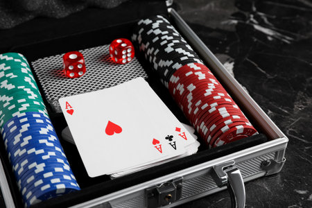 Gaming chips, dice and cards in suitcase on dark marble tableの写真素材