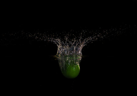 Apple falling down into clear water against black backgroundの写真素材