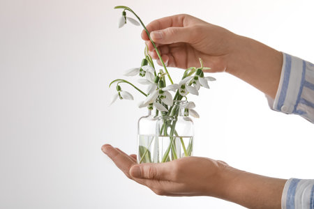 Woman holding glass jar with snowdrops on light background, closeupの写真素材