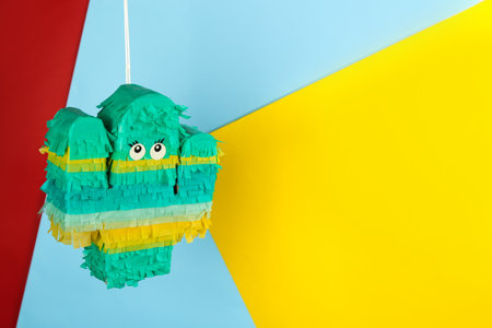 Cactus shaped pinata hanging on color background. Space for textの写真素材