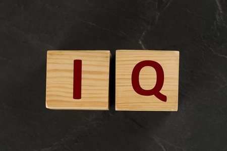 Wooden cubes with abbreviation IQ on black slate background, flat layの写真素材