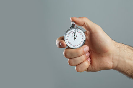 Man holding vintage timer on gray background, closeup. Space for textの写真素材