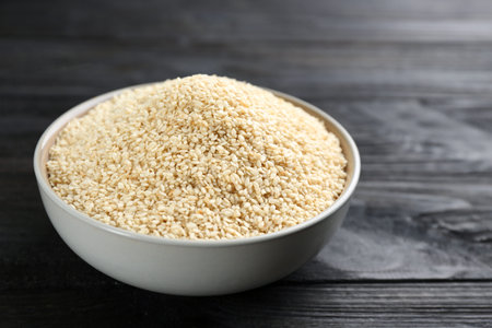 Sesame seeds in bowl on black wooden tableの写真素材