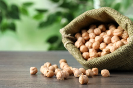 Raw chickpeas in bag on wooden table, closeup. Space for textの写真素材