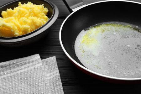Frying pan and bowl with Ghee butter on dark wooden table, closeupの写真素材