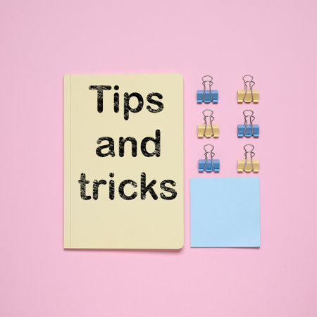 Notebook with text Tips and tricks on pink background, flat layの写真素材