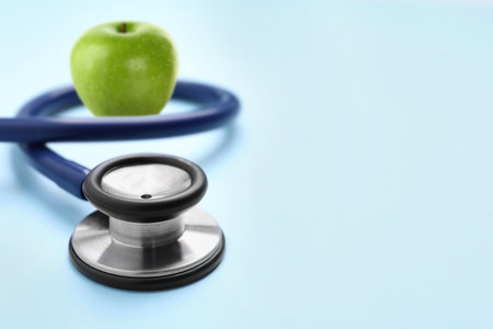 Stethoscope and green apple on light blue background, space for textの写真素材