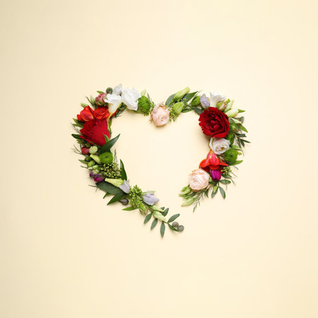 Beautiful heart made of different flowers on beige background, flat lay. Space for textの写真素材