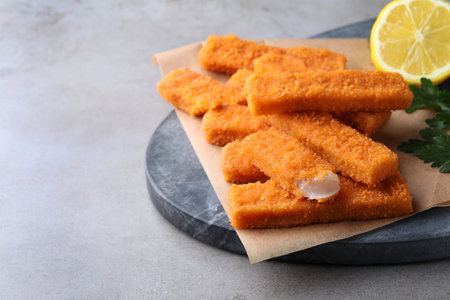 Fresh breaded fish fingers served on gray table, space for textの写真素材