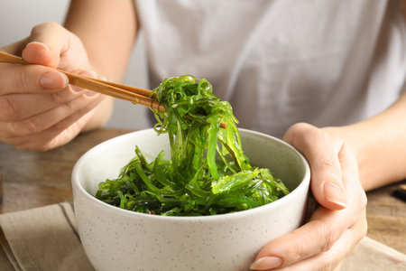 Woman eating Japanese seaweed salad at table, closeupの写真素材