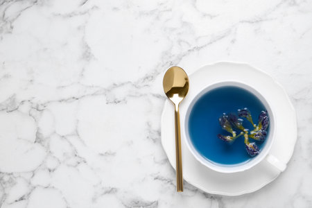 Organic blue Anchan in cup on white marble table, top view with space for text. herbal teaの写真素材