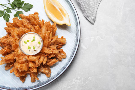 Fried blooming onion with dipping sauce served on light marble table, top view. Space for textの写真素材