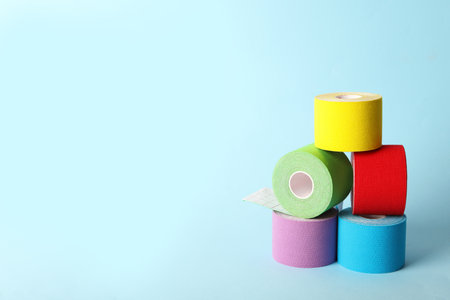 Bright kinesiology tape in rolls on light blue background. Space for textの写真素材