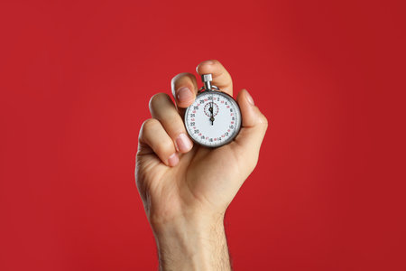 Man holding vintage timer on red background, closeupの写真素材