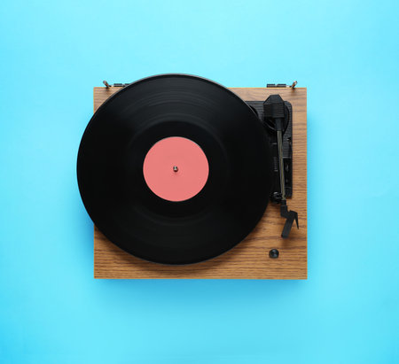 Modern turntable with vinyl record on light blue background, top viewの写真素材