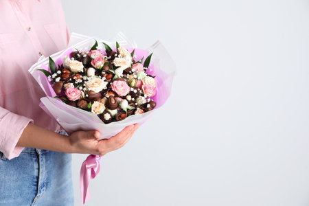 Woman with beautiful food bouquet on light gray background, closeup. Space for textの写真素材