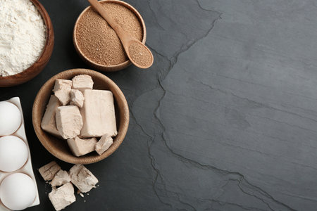 Yeast and dough ingredients on black table, flat lay. Space for textの写真素材