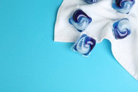 Laundry capsules and towel on light blue background, flat lay. Space for textの写真素材