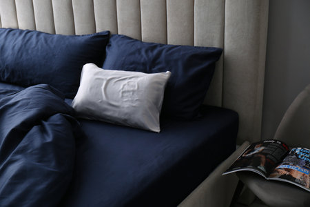 Bed with stylish silky linens in roomの写真素材