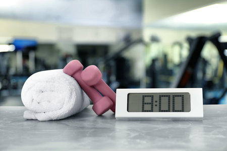 Digital clock, towel and dumbbells on marble surface in gym. morning exerciseの写真素材