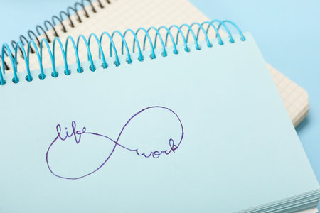 Drawn infinity sign with words Work and Life in notebook on light blue background, closeup. balance conceptの写真素材