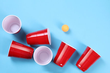 Plastic cups and balls on light blue background, flat lay. beer pong gameの写真素材