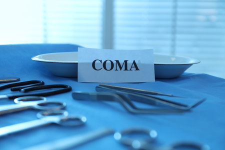 Card with word Coma and surgical instruments on table, closeup