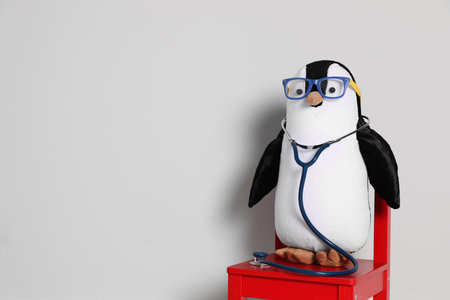 Toy penguin with eyeglasses and stethoscope on white background, space for text. Pediatric practiceの写真素材