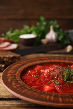 Stylish brown clay plate with Ukrainian borsch served on wooden table, closeupの写真素材