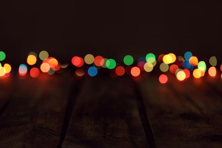 Blurred view of colorful lights on wooden table, space for textの写真素材