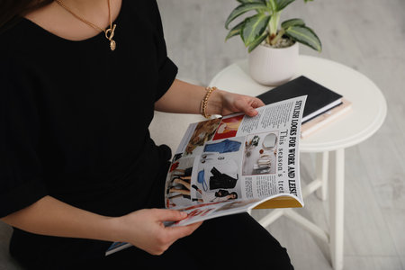Young woman reading fashion magazine indoors, closeupの写真素材