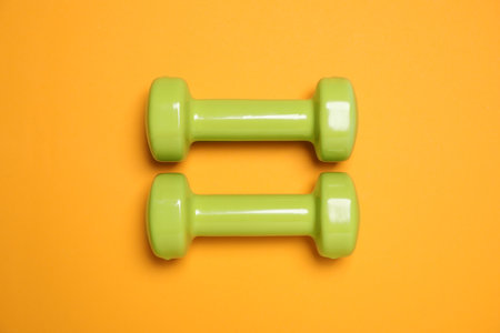 Dumbbells on orange background, flat lay. sport equipmentの写真素材