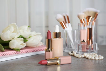 Different decorative cosmetics, brushes and white tulips on gray tableの写真素材