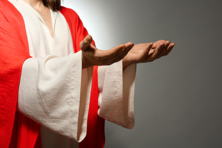 Jesus Christ reaching out his hands on gray background, closeupの写真素材