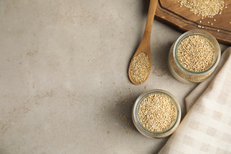 Jars and spoon with white quinoa on light gray table, flat lay. Space for textの写真素材