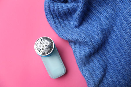 Modern fabric shaver and woolen sweater on pink background, flat layの写真素材