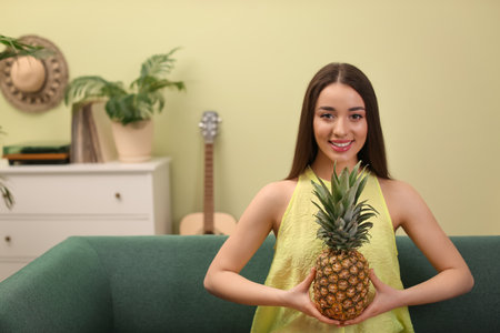 Young woman with fresh pineapple at home, space for text. exotic fruitsの写真素材
