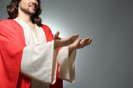 Jesus Christ reaching out his hands on gray background, closeup. Space for textの写真素材