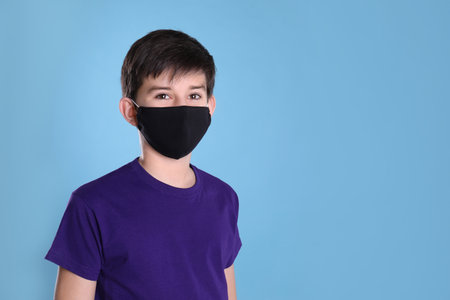 Boy wearing protective mask on light blue background, space for text. child safetyの写真素材