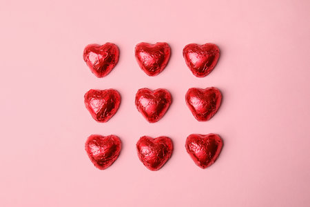 Heart shaped chocolate candies on pink background, flat lay. Valentine's day treatの写真素材