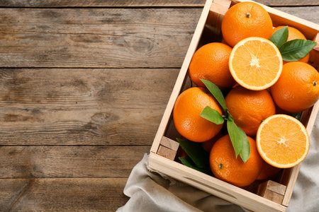 Delicious ripe oranges in crate on wooden table, top view. Space for textの写真素材