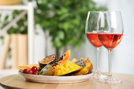 Delicious exotic fruits and glasses of wine on wooden table indoorsの写真素材