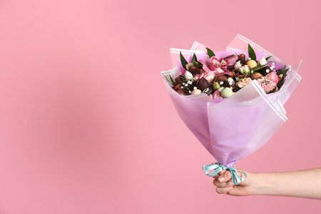 Woman with beautiful edible bouquet on pink background, closeup. Space for textの写真素材