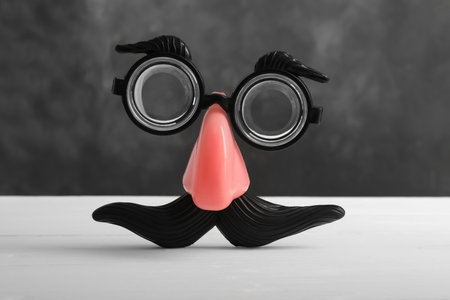 Funny face made with clown's accessories on white wooden tableの写真素材