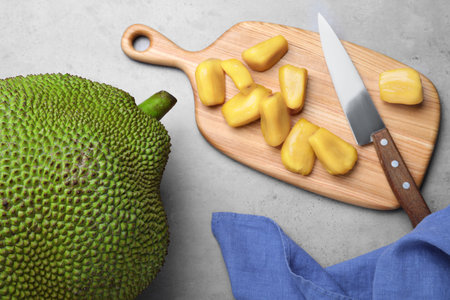 Delicious exotic jackfruit and bulbs on light gray table, flat lay