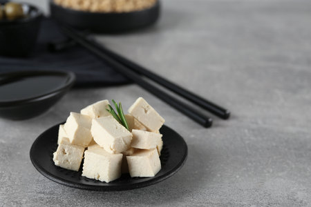 Pieces of delicious tofu with rosemary on gray table. Space for textの写真素材