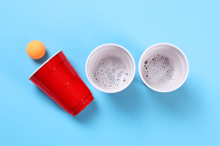 Plastic cups and balls for beer pong on light blue background, flat layの写真素材